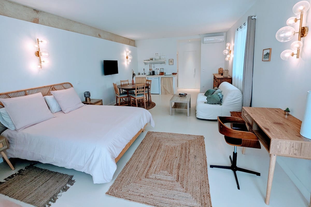 Un dormitorio con una cama grande, un escritorio de madera, un sofá y una mesa de comedor.
