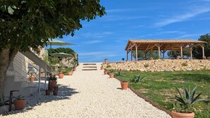 A gravel pathway leading to a covered outdoor area with potted plants and a clear blue sky. - Mas d'Eyrolles (Sainte-Anastasie)