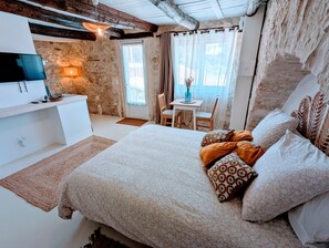A bedroom with a bed, a desk, and a TV. - Mas d'Eyrolles (Sainte-Anastasie)