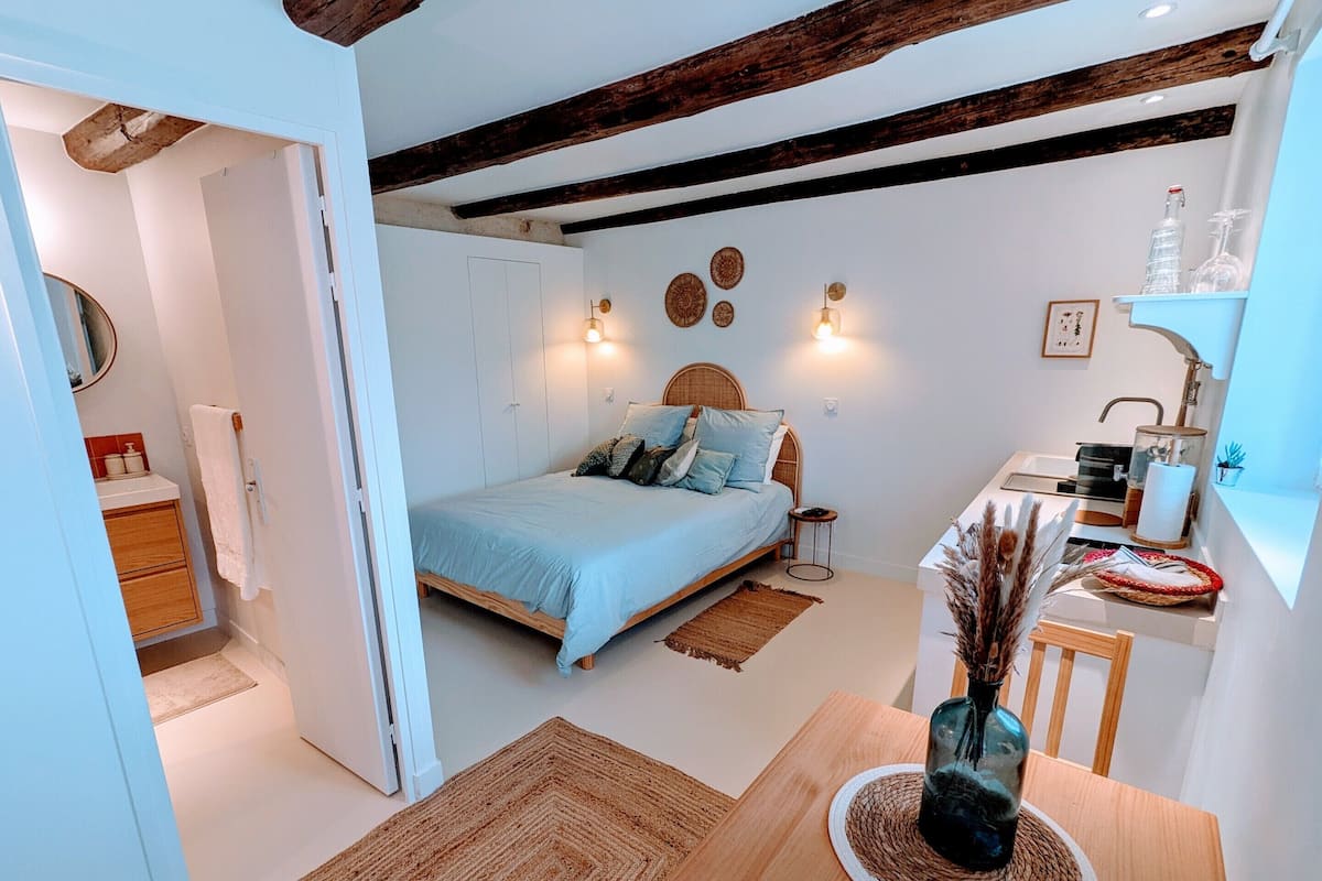 Un dormitorio con cama, mesita de noche y un pequeño escritorio con lámpara.