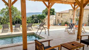 A wooden pergola with a pool and outdoor seating area. - Mas d'Eyrolles (Sainte-Anastasie)