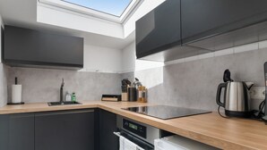 A modern kitchen with a skylight, built-in appliances, and a wooden countertop.