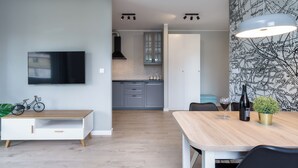 A modern kitchen with grey cabinets, a black range hood, and a window above the sink. - Wałowa - Garden View by Grand Apartments (Gdansk)