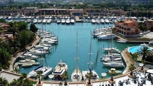 A marina with numerous boats docked, surrounded by buildings and greenery. - Portorosa Beach Resort (Tonnarella)