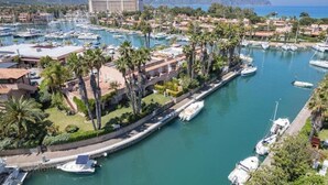 A marina with boats docked, surrounded by residential buildings and palm trees. - Portorosa Beach Resort (Tonnarella)