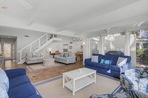 A spacious living room with a staircase, two sofas, a coffee table, and a dining area.
