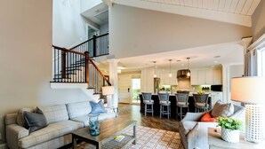 A spacious living area with a high ceiling, a staircase, and a kitchen in the background. - 213 Twin Oaks at The Sea Pines Resort (Hilton Head Island)