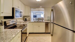A modern kitchen with stainless steel appliances, white cabinetry, and a granite countertop. - 436 Plantation Club Villas at The Sea Pines Resort (Hilton Head Island)