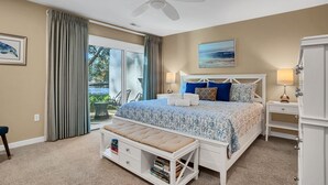 A bedroom with a bed, bedside tables, a bench, and a view of the outdoors.