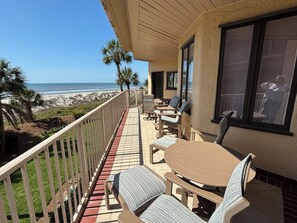 A balcony with a view of the beach, outdoor seating, and a large window. - 201 Turtle Lane at The Sea Pines Resort (Hilton Head Island)