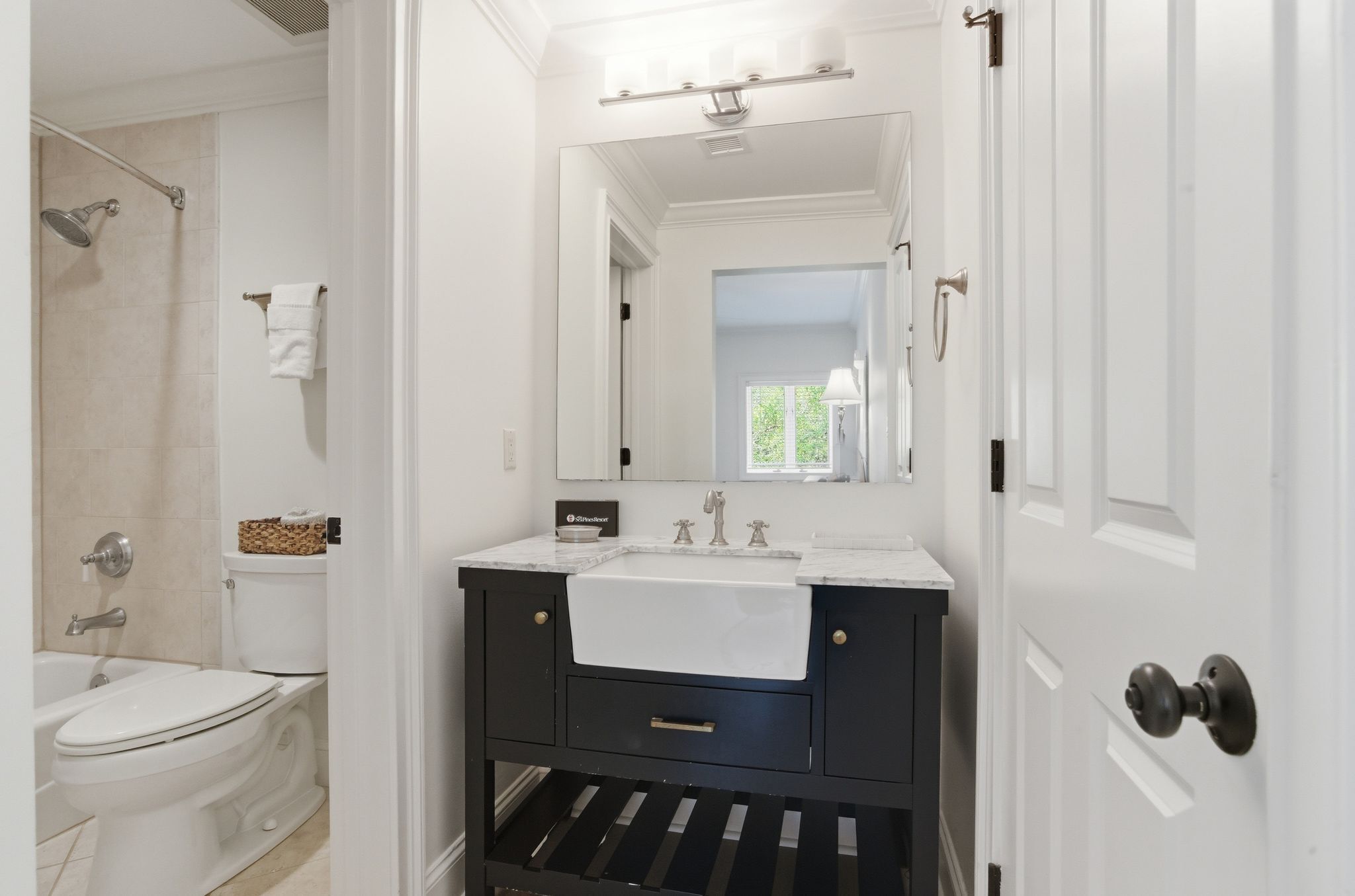 Een badkamer met een wit toilet, een douche, een wastafel met spiegel en een handdoekhouder.