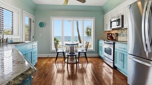 A kitchen with a view of the beach, a ceiling fan, and a dining area with a table and chairs. - 201 Turtle Lane at The Sea Pines Resort (Hilton Head Island)