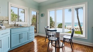 A kitchen with a blue cabinet, a dining table with chairs, and a view of the beach. - 201 Turtle Lane at The Sea Pines Resort (Hilton Head Island)