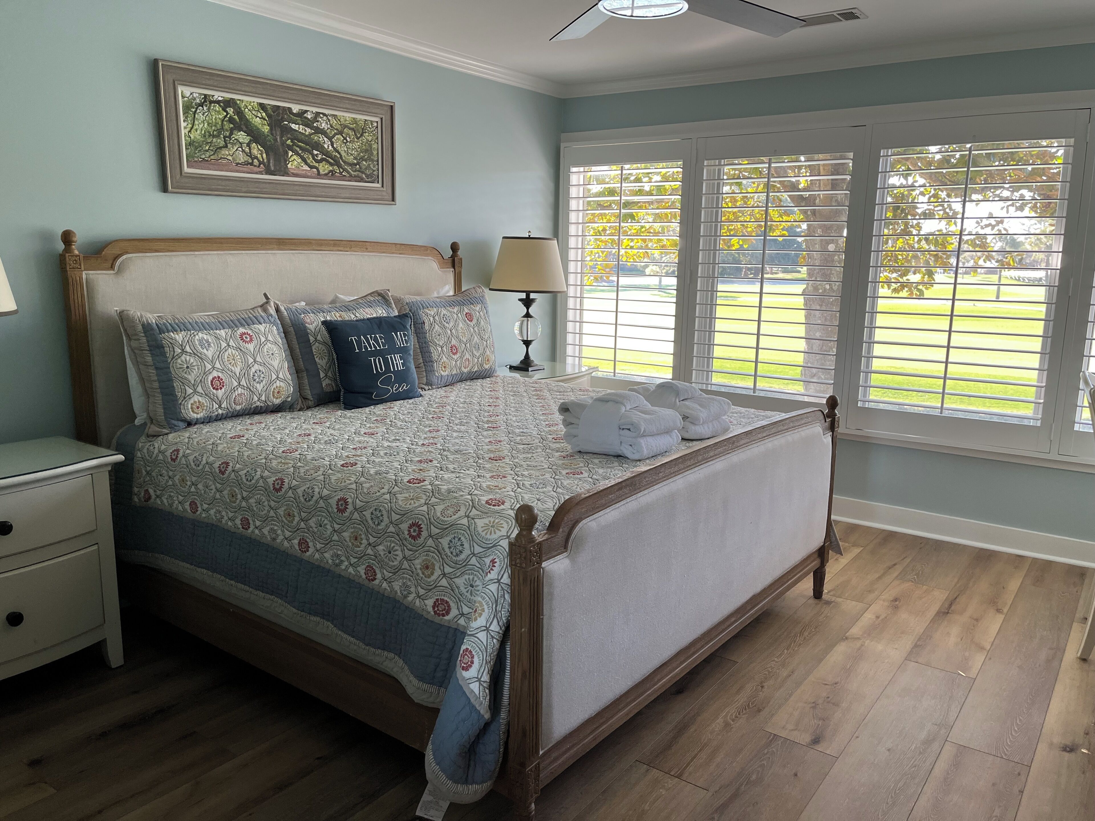 A bedroom with a bed, a nightstand, a lamp, and a window with blinds.