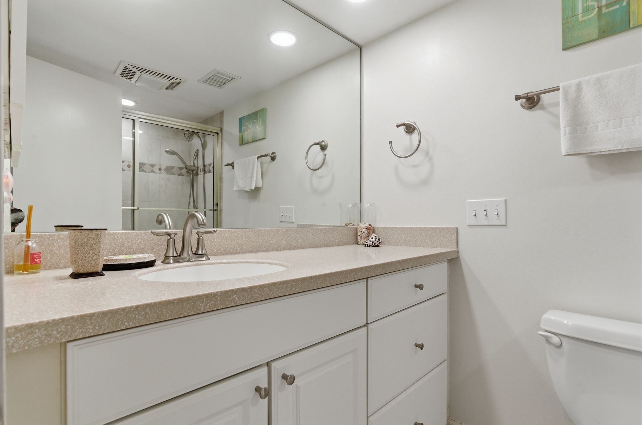 Une salle de bain équipée d’un lavabo, d’un miroir, de porte-serviettes et de toilettes.