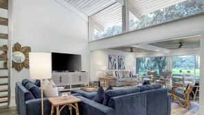 A spacious living room with a large sectional sofa, a flat-screen TV, and a dining area with wicker chairs. - 80 Fairway Lane at The Sea Pines Resort (Hilton Head Island)