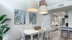 A modern kitchen with white cabinetry, a dining area with a white table and chairs, and two pendant lights. - 80 Fairway Lane at The Sea Pines Resort (Hilton Head Island)