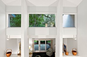A multi-level interior with large windows offering views of a forested area. - 298 Stoney Creek Villa at The Sea Pines Resort (Hilton Head Island)
