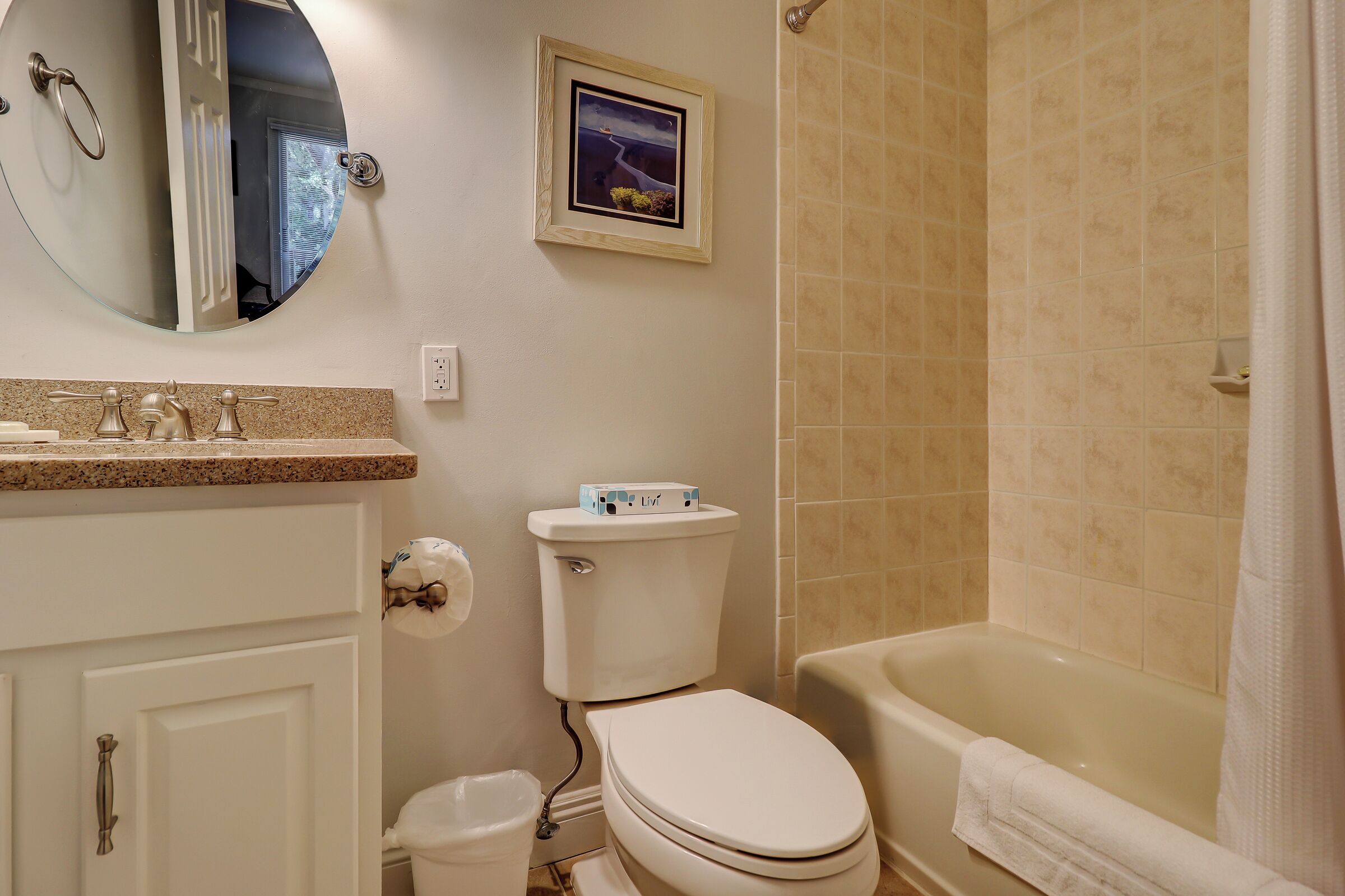 A bathroom with a toilet, sink, mirror, and bathtub.
