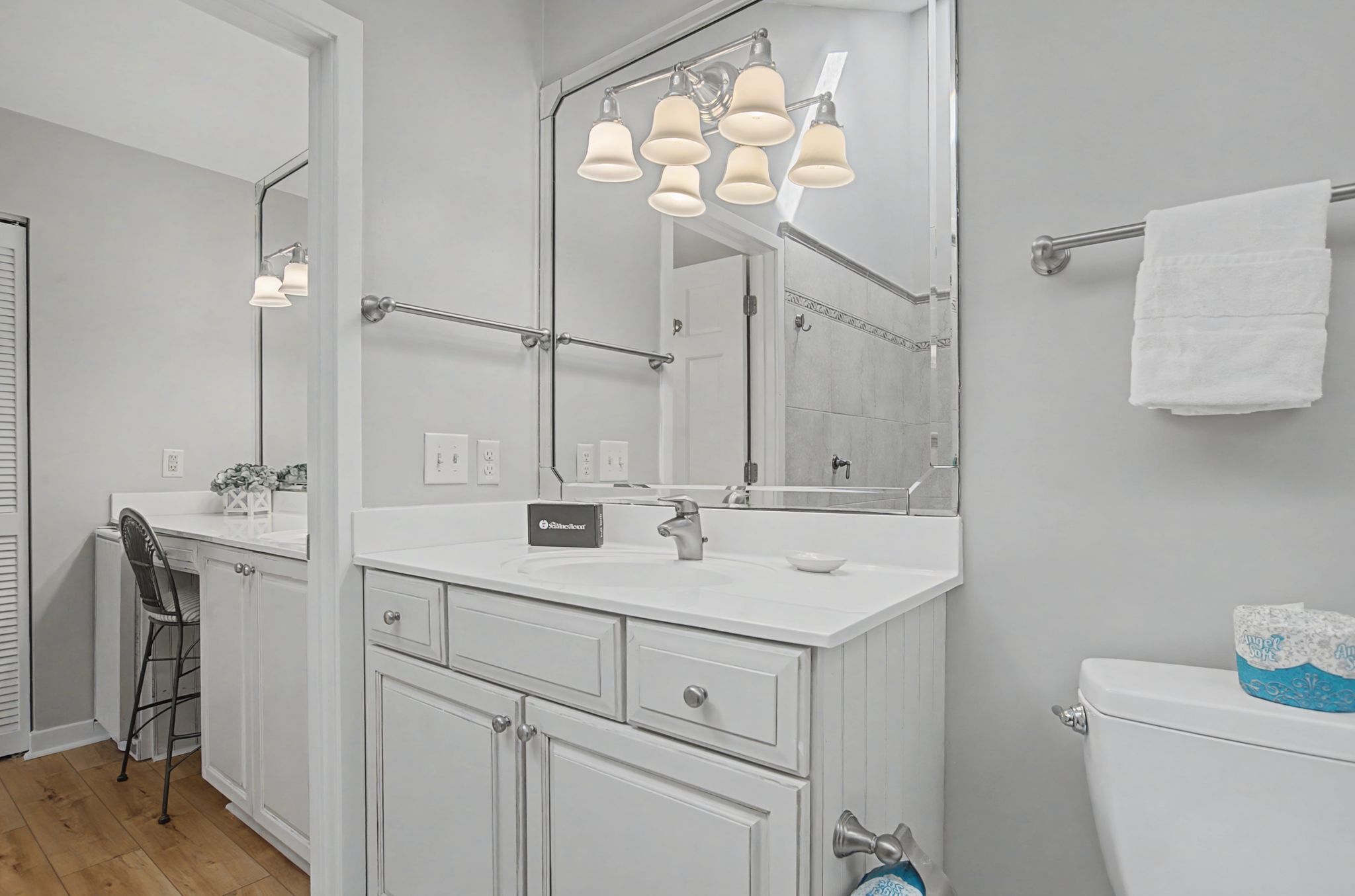 A modern bathroom with a white vanity, a large mirror, and a towel rack.