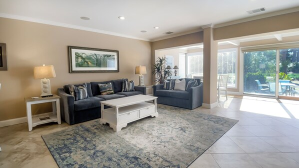 A spacious living room with two sofas, a coffee table, and a large window offering a view of the outdoors. - 153 Harbourwood Villa at The Sea Pines Resort (Hilton Head Island)