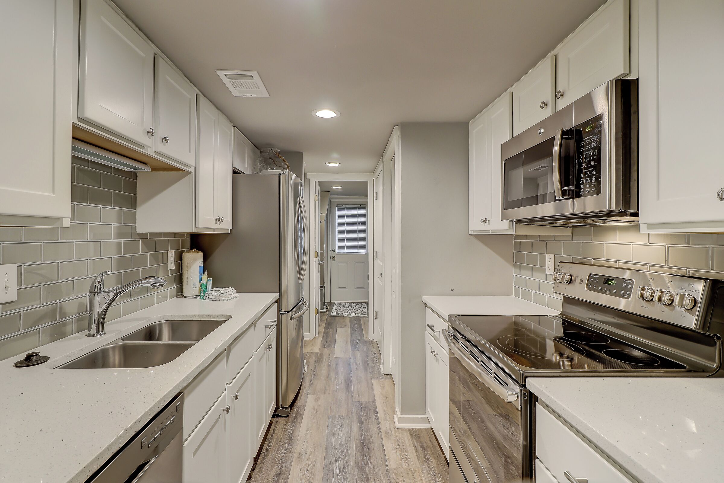 Una cocina moderna con armarios blancos, electrodomésticos de acero inoxidable y salpicadero de azulejos.