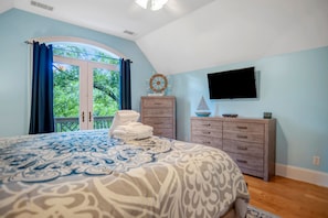 A bedroom with a large bed, a dresser, a television, and a window with curtains. - 64 Lawton Road at The Sea Pines Resort (Hilton Head Island)