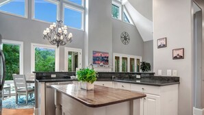 A spacious kitchen with a central island, large windows, and a chandelier. - 64 Lawton Road at The Sea Pines Resort (Hilton Head Island)