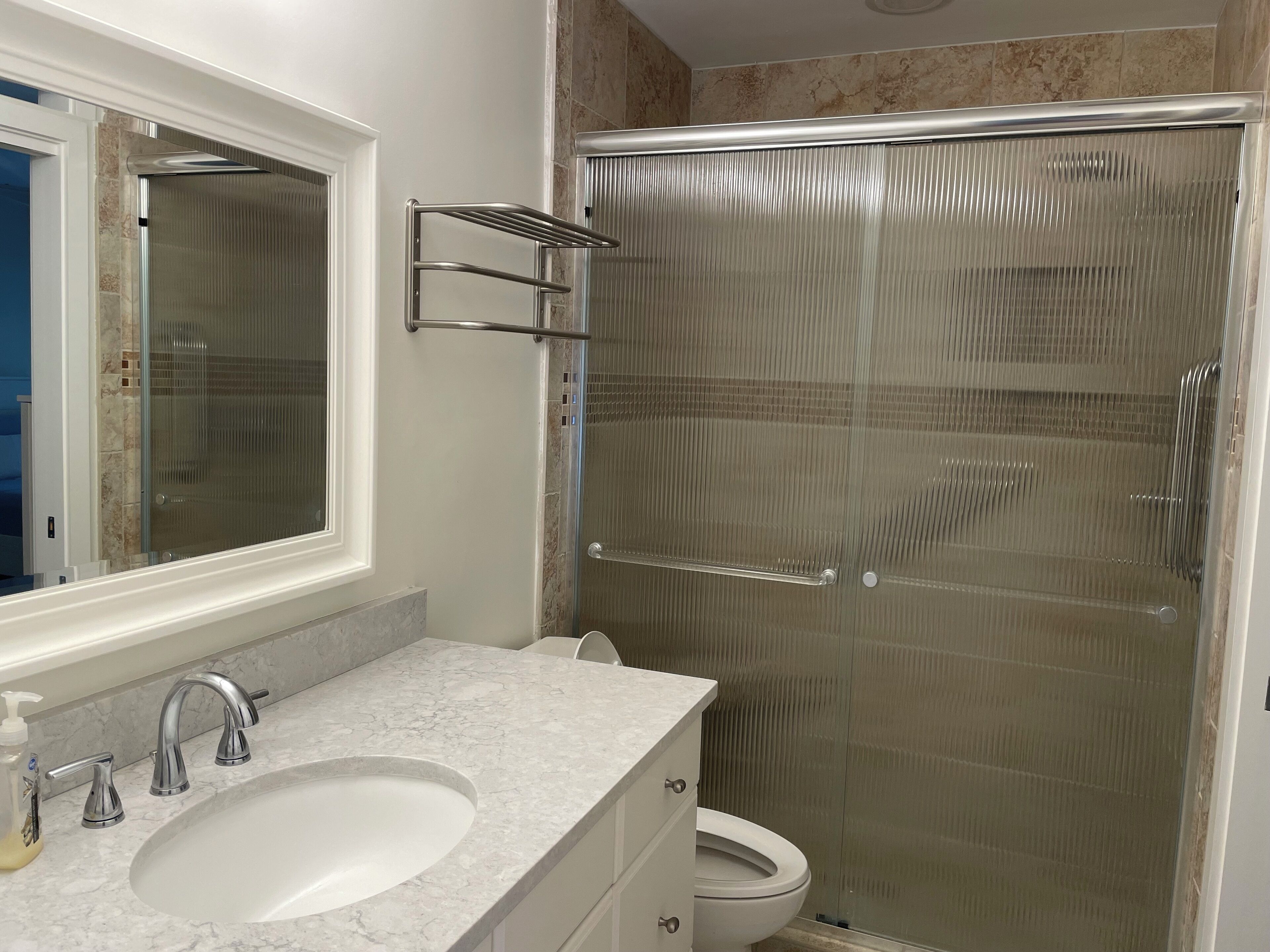 Ein Badezimmer mit Marmorwaschbecken, Toilette und einer Duschkabine aus Glas.