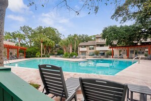 A swimming pool with lounge chairs and a covered seating area, surrounded by trees and buildings. - 290 Stoney Creek Villa at The Sea Pines Resort (Hilton Head Island)