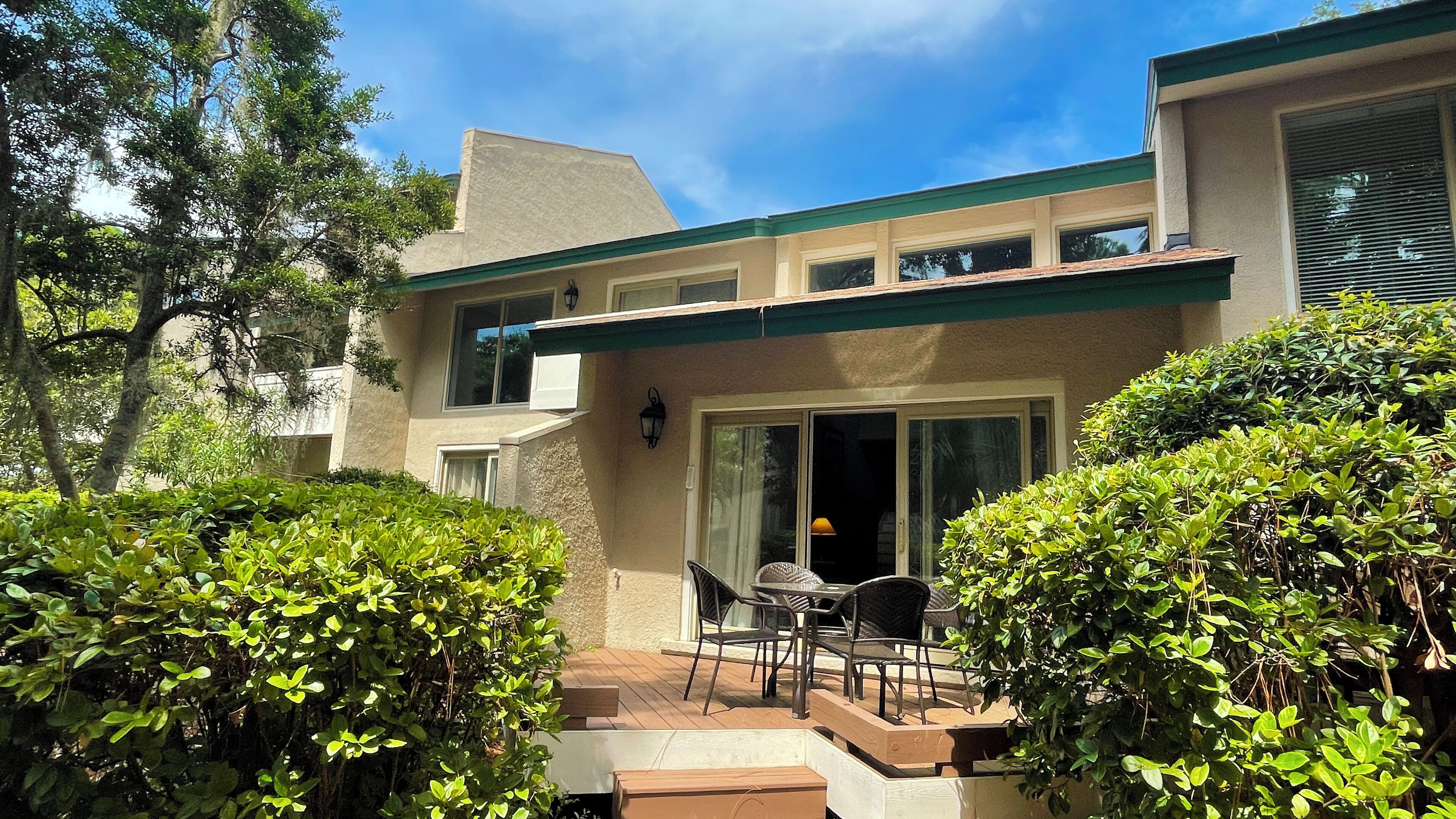 A two-story house with a patio area, a sliding glass door, and a small outdoor seating area with a table and chairs.