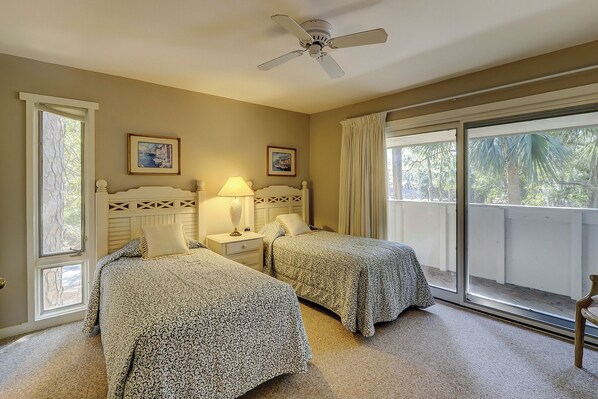 A bedroom with two beds, a ceiling fan, and a large window with curtains. - 238 Stoney Creek Villa at The Sea Pines Resort (Hilton Head Island)