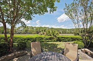 An outdoor seating area with two chairs and a table, surrounded by greenery and trees. - 259 Stoney Creek Villa at The Sea Pines Resort (Hilton Head Island)