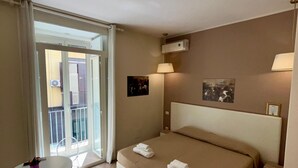 A hotel room with a large bed, a small table, and a balcony with a view. - de Ribera rooms (Naples)