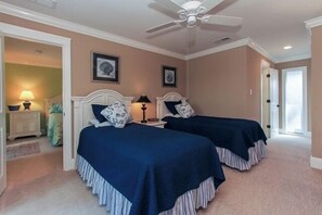 Ein Schlafzimmer mit zwei Betten, einem Deckenventilator und einer Tür zu einem weiteren Raum.