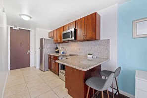 A cozy wooden kitchen featuring essential appliances and stocked wit some basics needed for cooking.