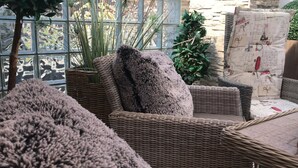 Mobilier en osier agrémenté d’un coussin moelleux, d’un panier tressé et d’un autre coussin orné d’un motif d’époque.