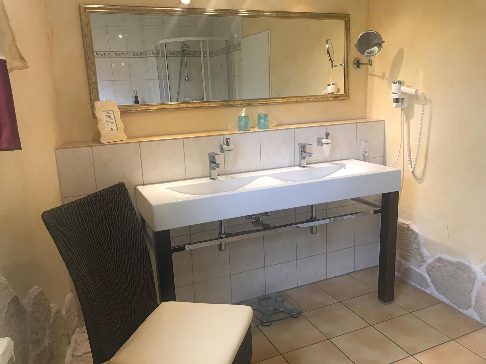 A bathroom with a white sink, a mirror, a shower, and a towel rack.