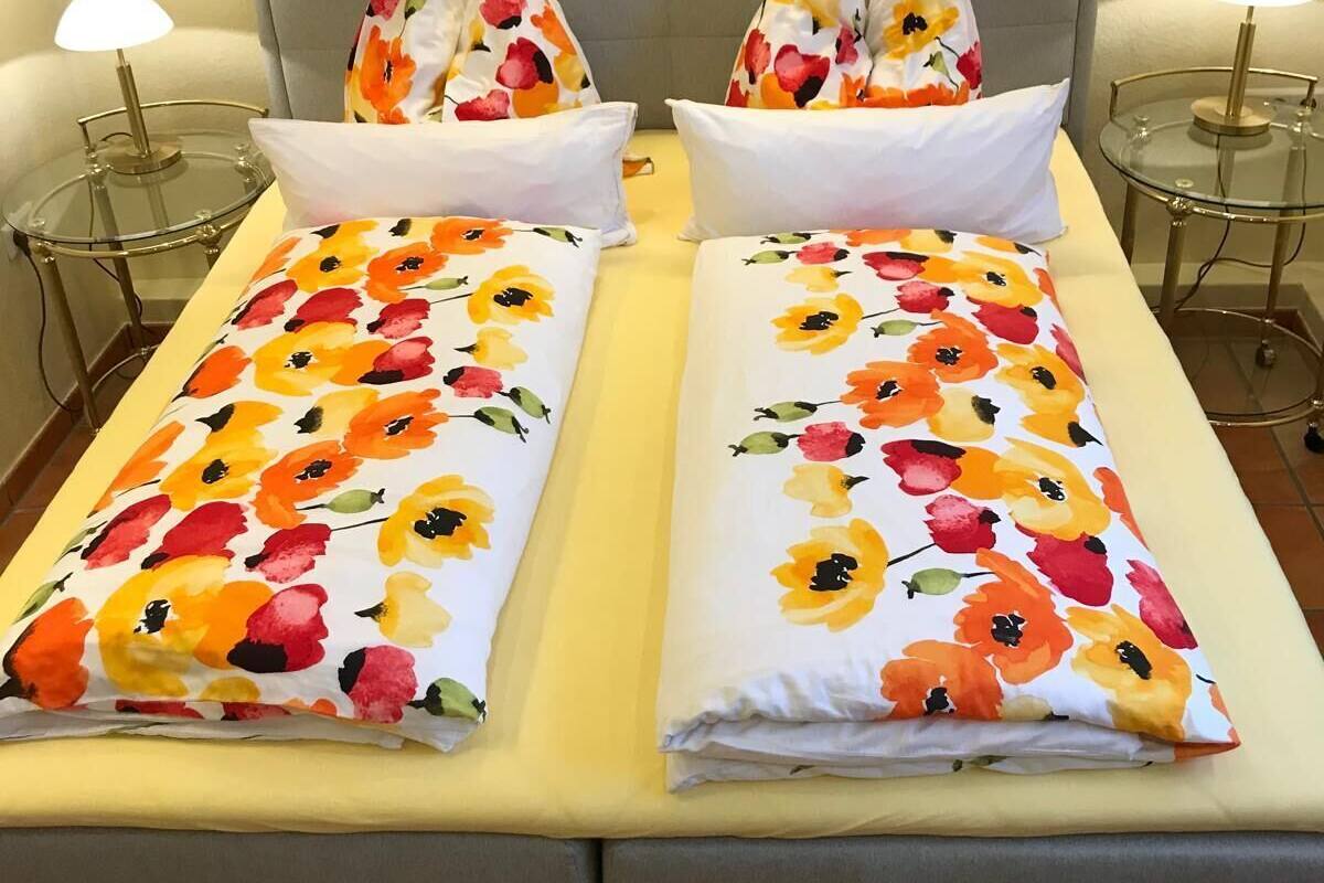 Una cama con ropa de cama floral, dos mesitas de noche y lámparas.