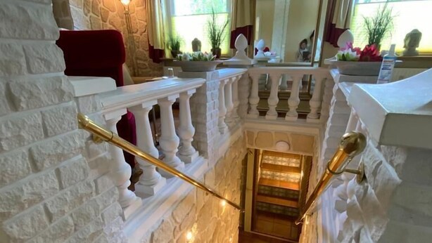 Un escalier aux murs en pierre blanche et doté d’une balustrade, menant à un niveau inférieur.