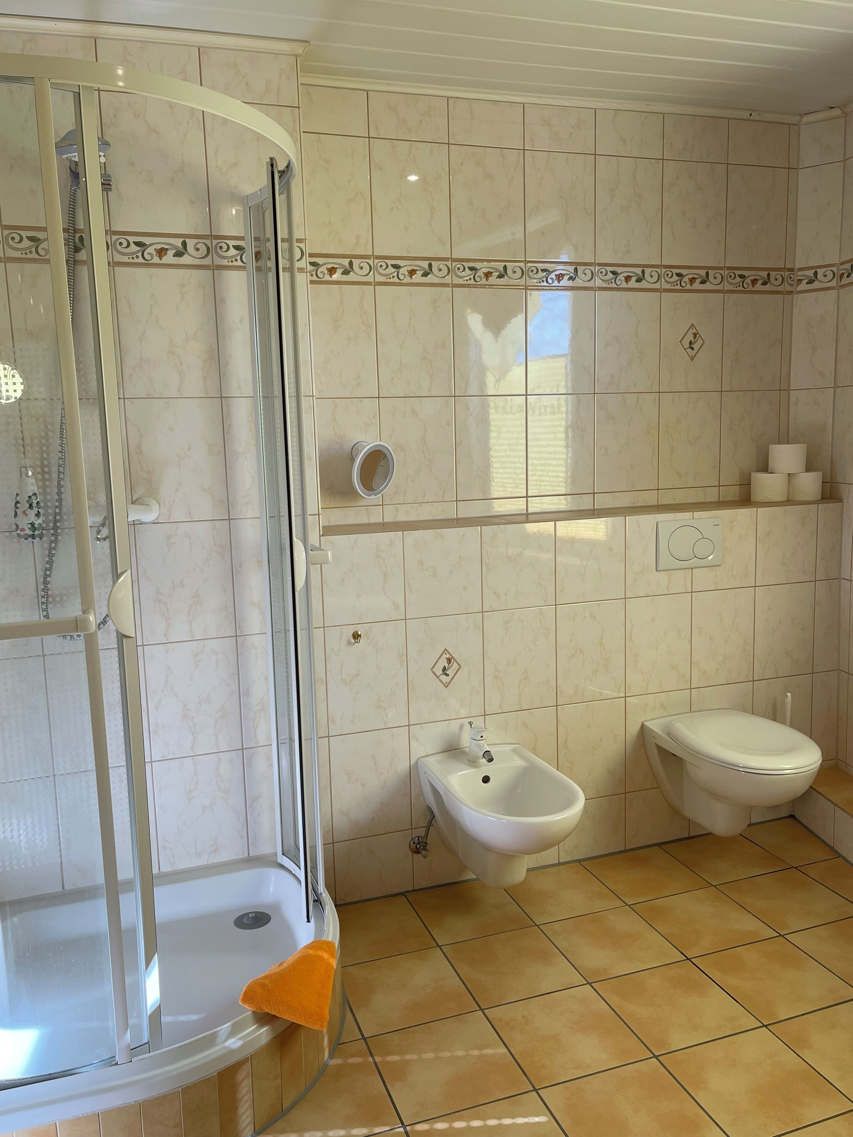 A bathroom with a glass shower enclosure, a sink, a bidet, and a toilet.