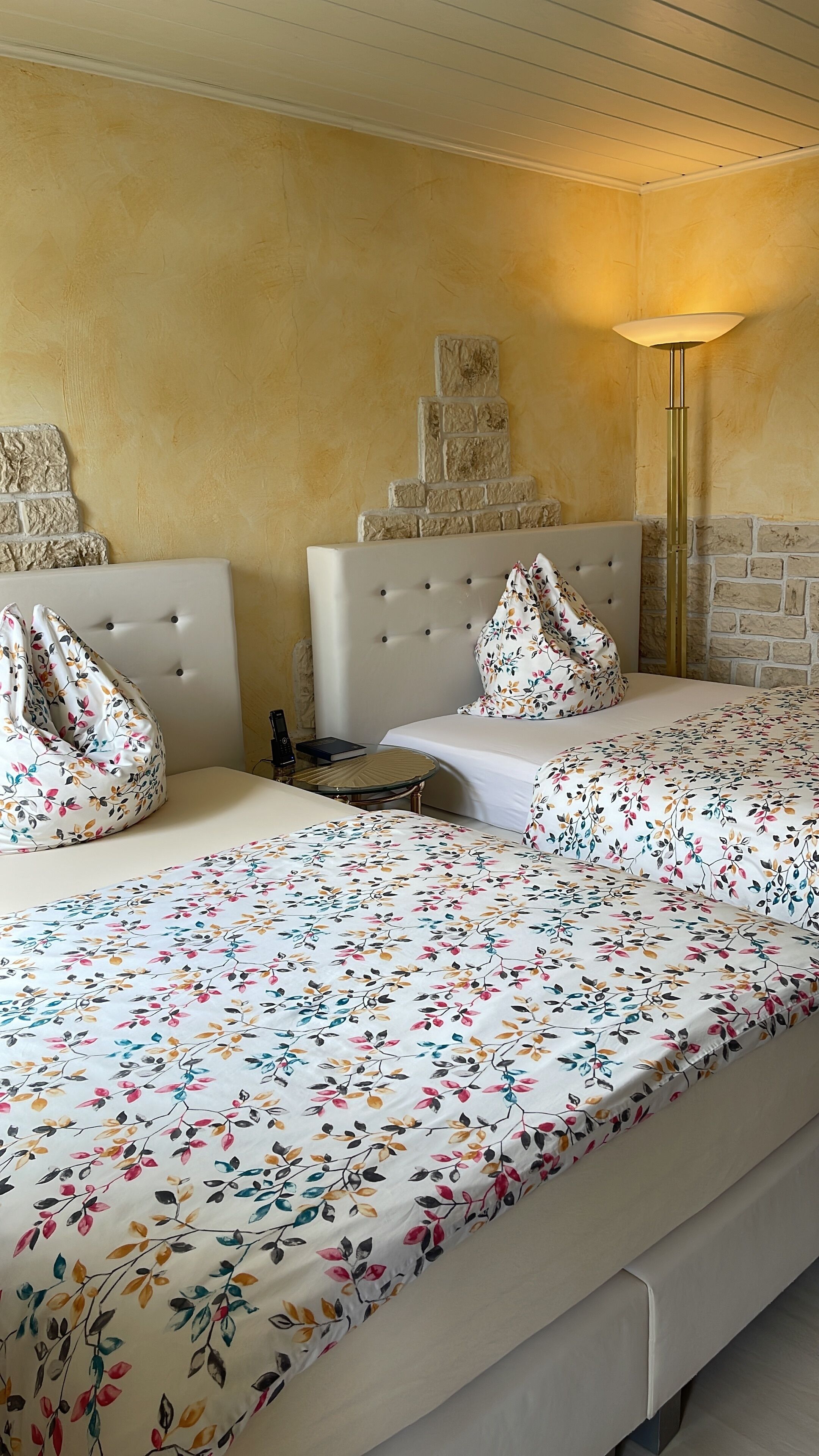 A hotel room with a large bed, a small table, and a lamp.