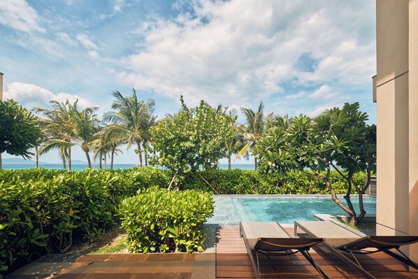 A pool area with lounge chairs, surrounded by lush greenery and palm trees, overlooking the ocean. - Ocean Sun Pool Villas Resort Cam Ranh (Cam Lam)