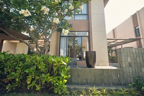 A modern building with a large window, a concrete planter, and lush greenery. - Ocean Sun Pool Villas Resort Cam Ranh (Cam Lam)