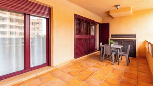 A balcony with a tiled floor, a table with chairs, and a potted plant. - DREAM SEA APARTMENTS - 1 BEDROOM (El Ejido)