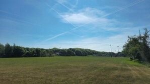 A wide, open grassy field with a clear sky and distant trees. - Nine Yards Bell Tents - Lytham (Lytham St. Anne's)