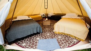 A tent with two beds, a hanging light, and a small table with a candle. - Nine Yards Bell Tents - Lytham (Lytham St. Anne's)
