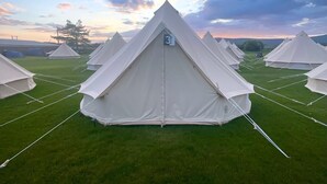 A row of white tents arranged in a field with a clear sky. - Nine Yards Bell Tents - Lytham (Lytham St. Anne's)