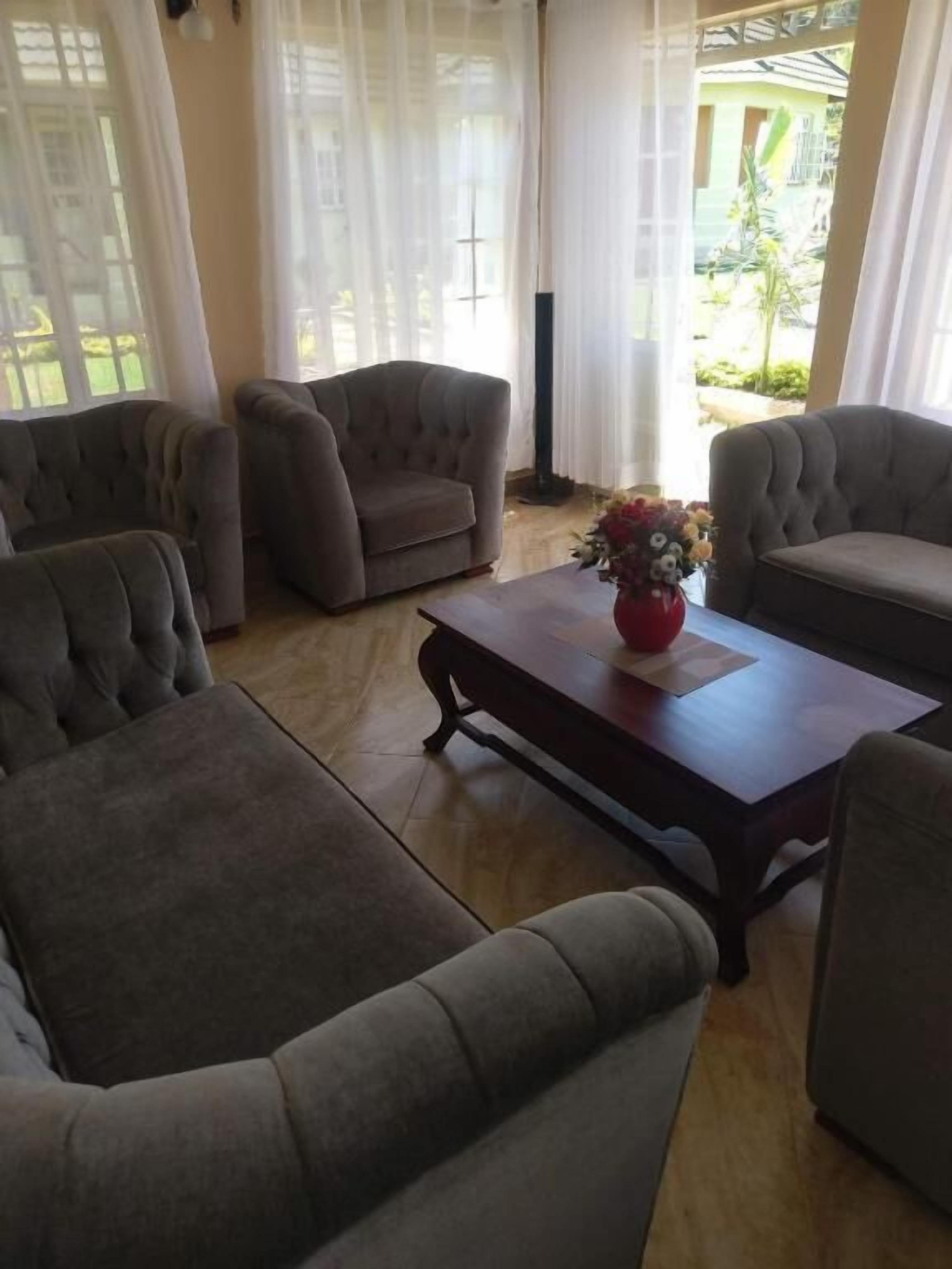 Un salón con un sofá, una mesa de centro y un jarrón con flores.