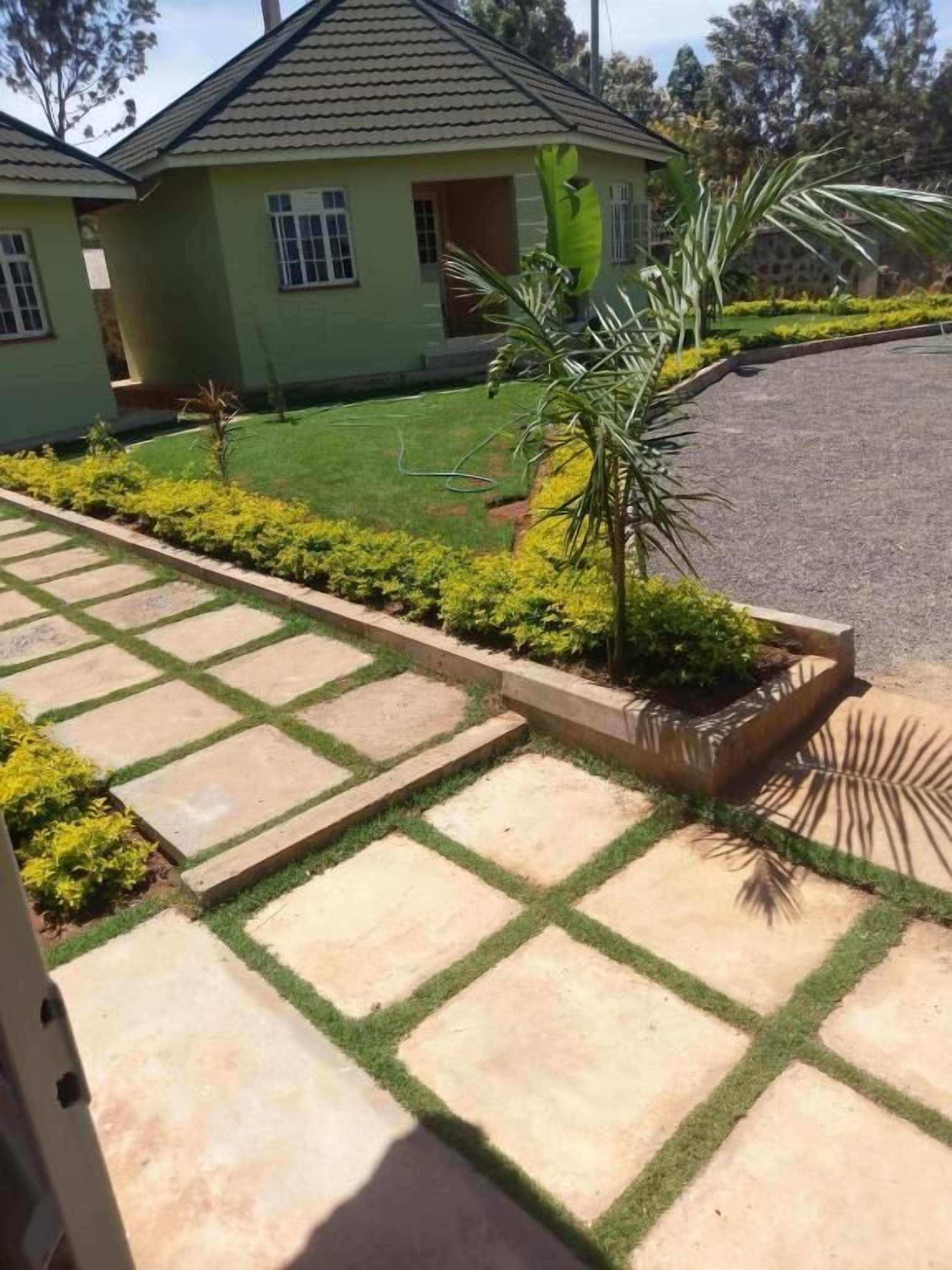 A residential property with a paved driveway, a lawn, and a house with a tiled roof.